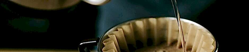 Close-up of a manual pour over coffee brewing process, highlighting the coffee and filter.